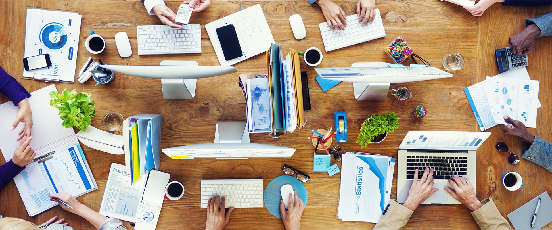 Ein Konferenztisch mit mehreren Laptops / PCs und Notizmaterialien.